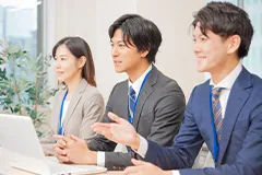 スーツを着た男性二人と女性一人が話している