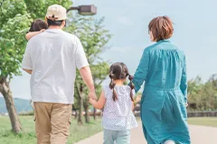手をつないで歩く4人家族の後ろ姿