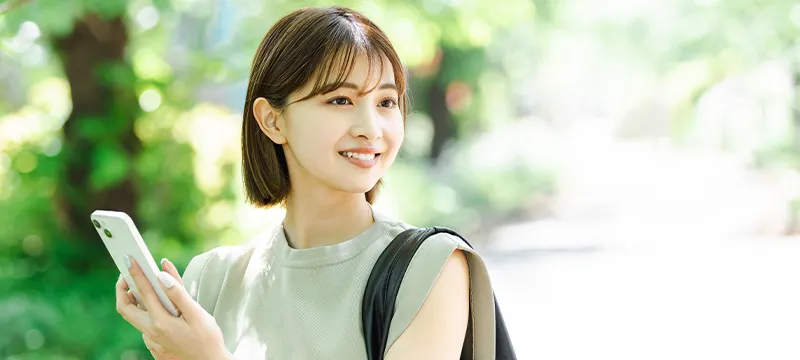 公園でスマホをもって周囲を見回す女性